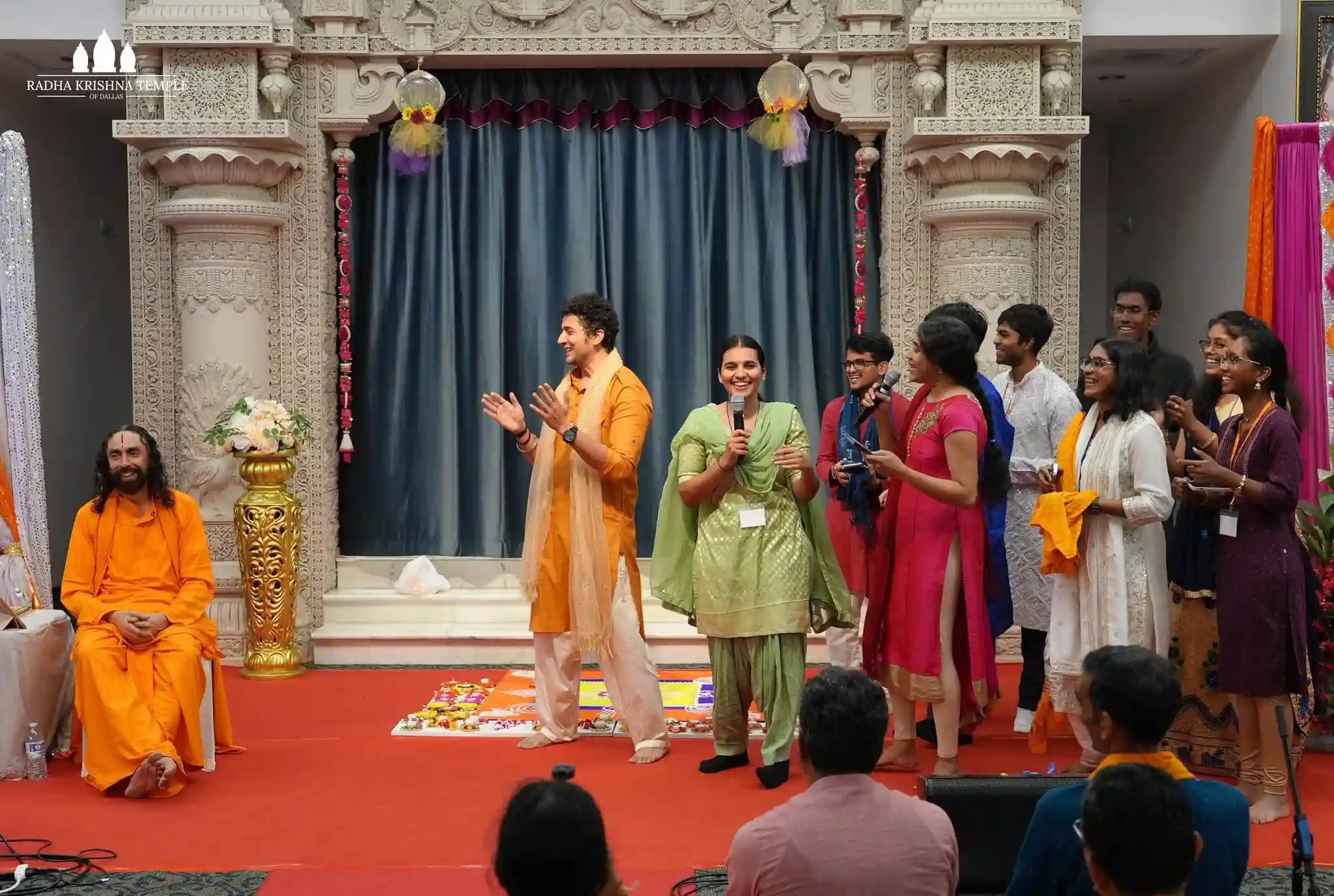 A group of people singing joyfully alongside their Guru, Swami Mukundanandaji