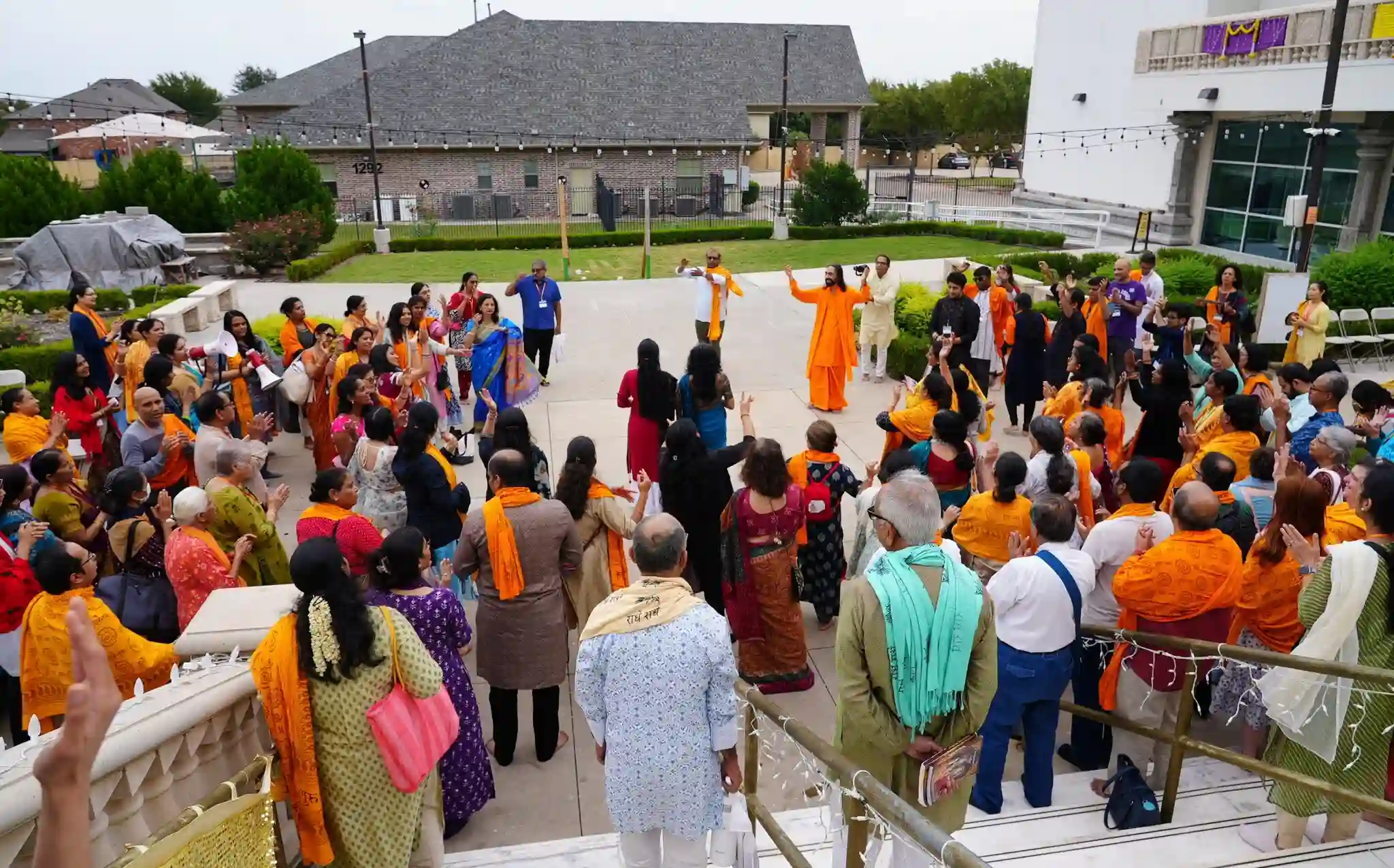 A grand crowd of men and women standing outside along side Swami Mukundanandaji cheering and having fun
