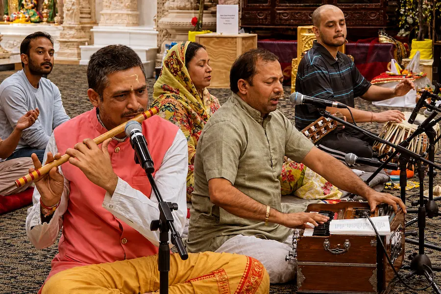 Devotional musicians performing bhajan kirtan with harmonium flute and tabla at Radha Krishna Temple Dallas