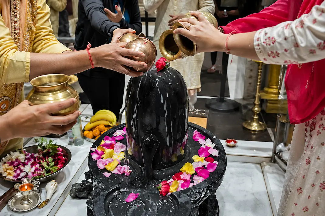 Devotee performing Shiv Abhishek by pouring water over Shivling at Radha Krishna Temple Dallas