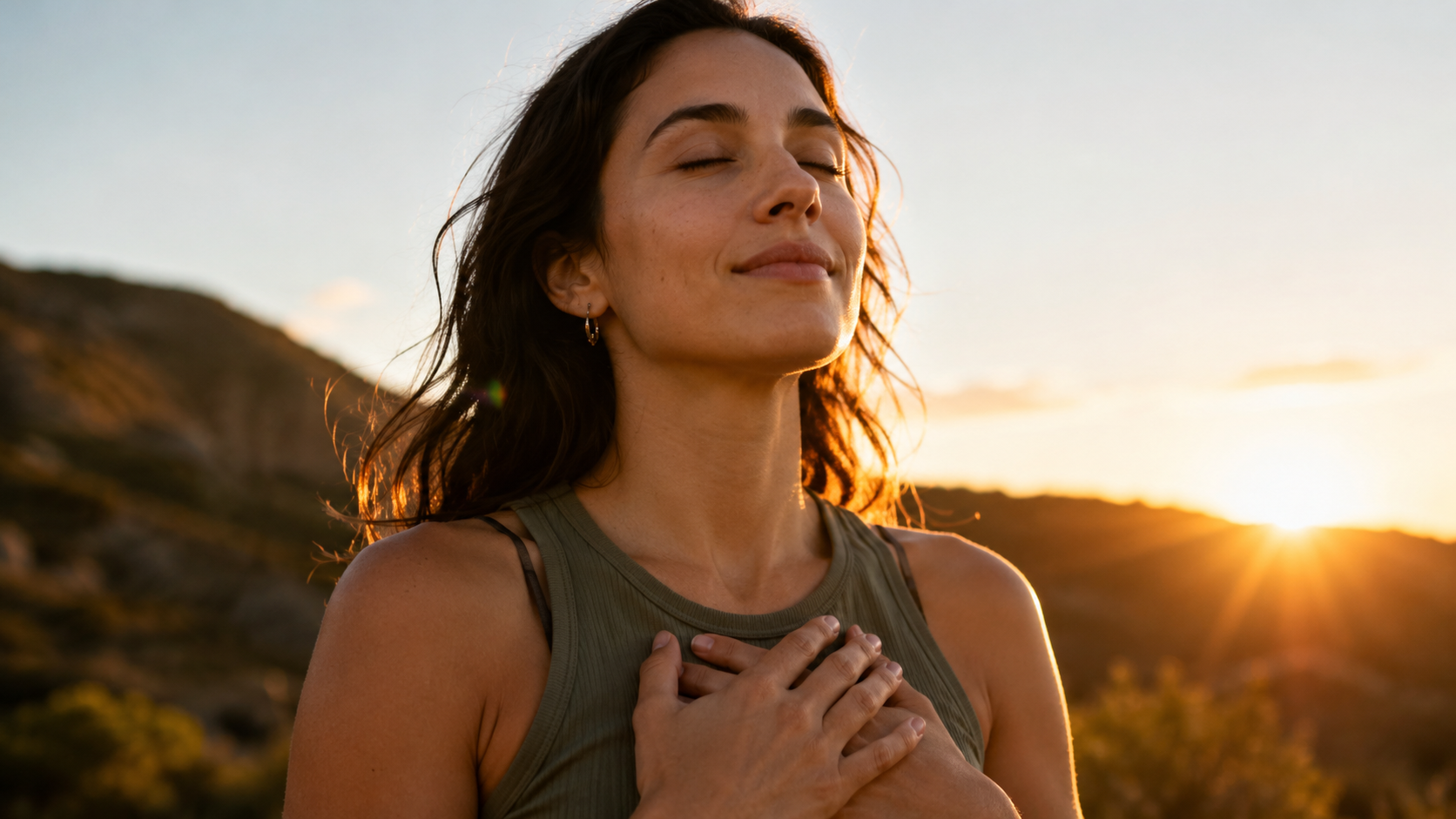 A woman stands calmly at sunset with hands over her heart, representing the article’s idea that every soul carries an inner spiritual power awakened through devotion.