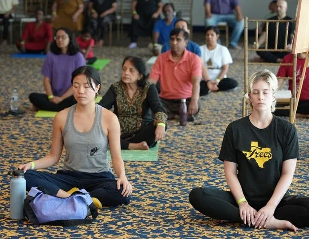 Participants practicing meditation and pranayama outdoors at Radha Krishna Temple of Dallas during International Yoga Day at sunrise.