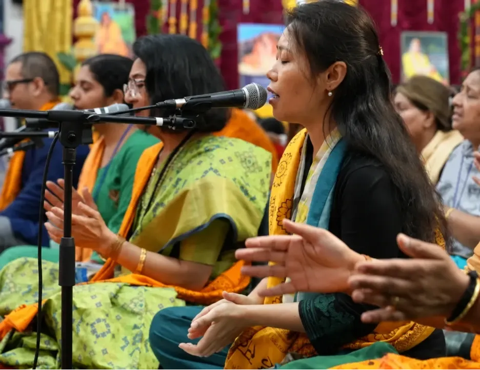 Devotees singing kirtan with microphones during a devotional gathering at Radha Krishna Temple of Dallas