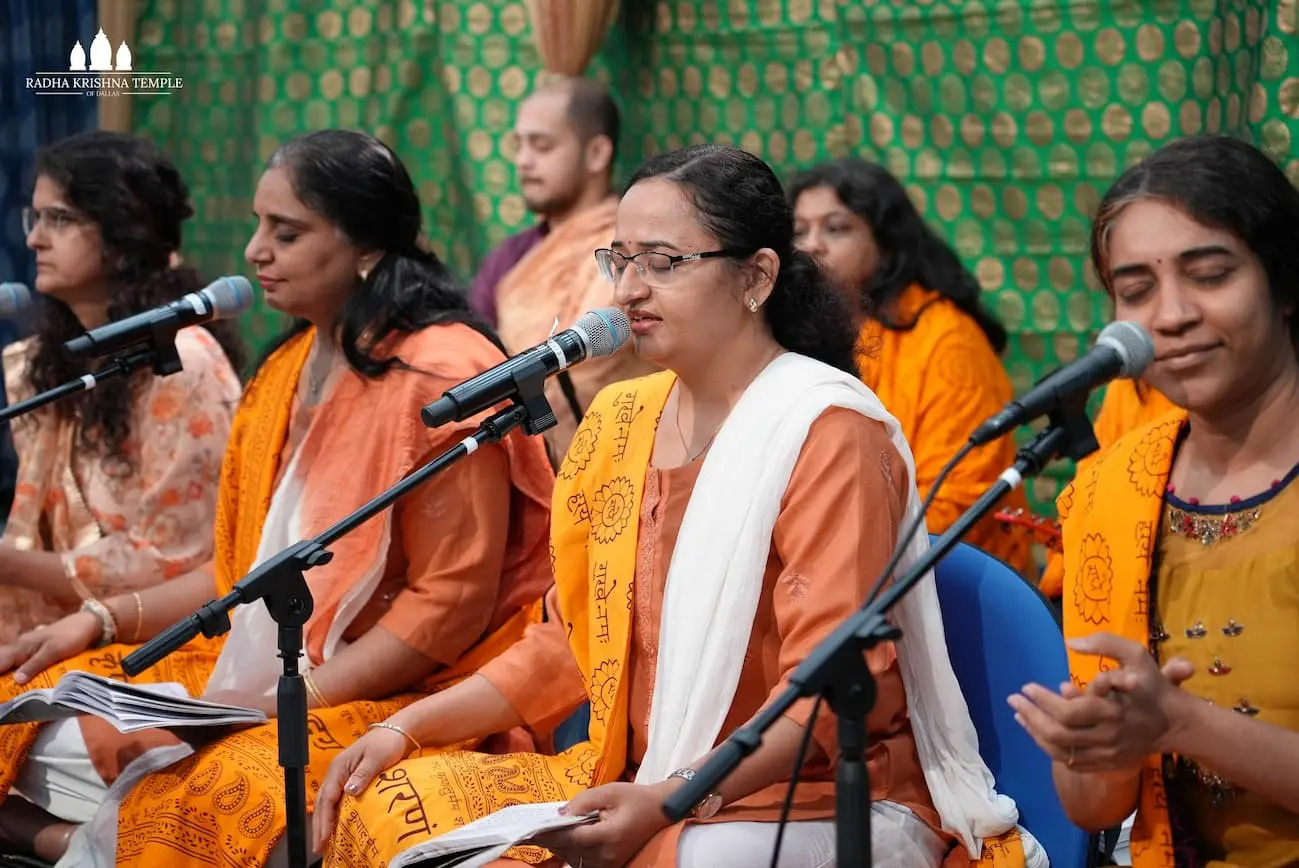 Women in traditional attire singing devotional kirtans into microphones during the Dallas Spiritual Retreat