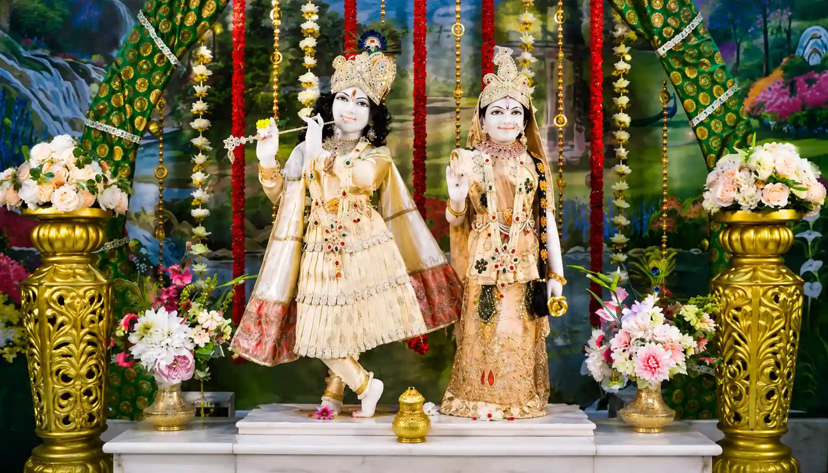 Shree Radha Krishna deities dressed in cream and gold garments, decorated with garlands and flowers at Radha Krishna Temple of Dallas