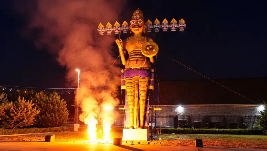 Families gather for a grand Dussehra Ravan Dahan celebration as the ten-headed Ravan effigy burns beside a beautifully illuminated Hindu temple